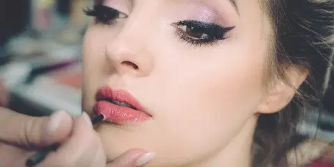 Close-up of a makeup artist applying lip liner to a client's face.