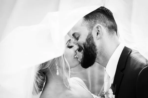 Black and white close-up of a bride and groom smiling and touching foreheads.