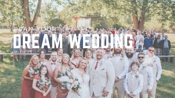 A large wedding party and guests posing for a group photo outdoors at a wedding event.