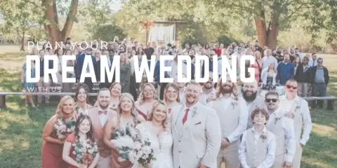 A large wedding party and guests posing for a group photo outdoors at a wedding event.