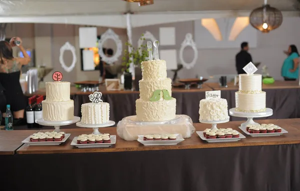 A wedding dessert table featuring several white tiered cakes and cupcakes on stands.