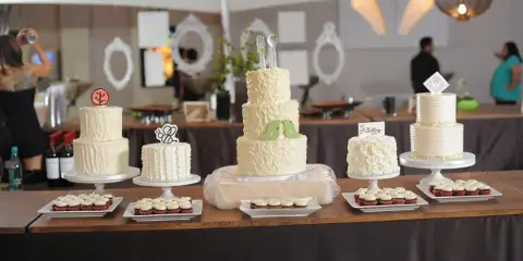 A wedding dessert table featuring several white tiered cakes and cupcakes on stands.