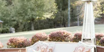 An outdoor event lounge setup featuring a white sofa, gold coffee tables, and a patio heater.