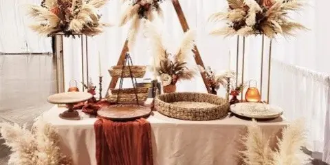 A professionally decorated event table featuring floral arrangements, pampas grass, and rustic centerpieces.