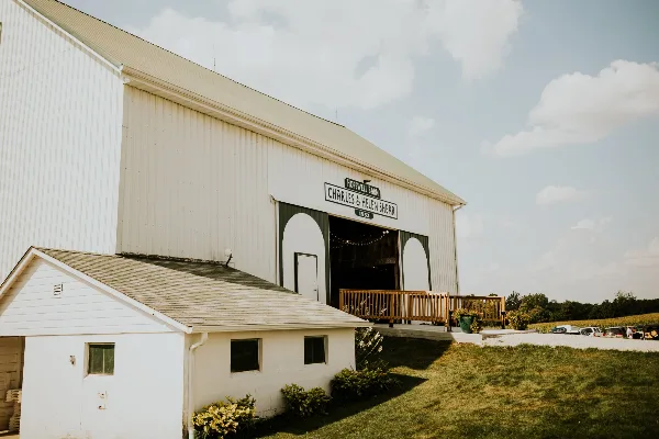 Exterior view of a large white barn with a sign reading 'Hopewell Barn Charles & Helen Shear 1953'.
