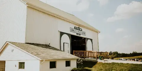 Exterior view of a large white barn with a sign reading 'Hopewell Barn Charles & Helen Shear 1953'.