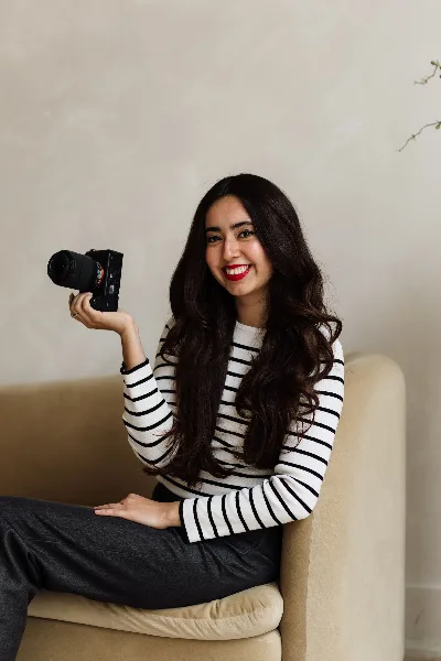 A woman sitting on a chair holding a professional camera.