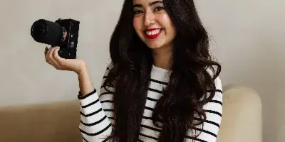 A woman sitting on a chair holding a professional camera.