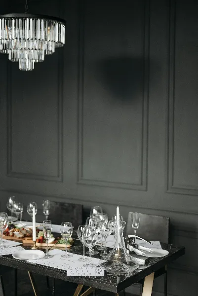 A styled event table with glassware, candles, and a crystal chandelier in a dark paneled room.