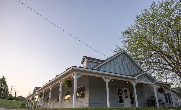 Exterior view of the Grow Benzie event center building featuring a long porch, string lights, and a gabled roof.