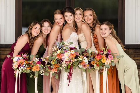 A bride and her bridesmaids posing together with bouquets, showcasing styled hair and makeup.