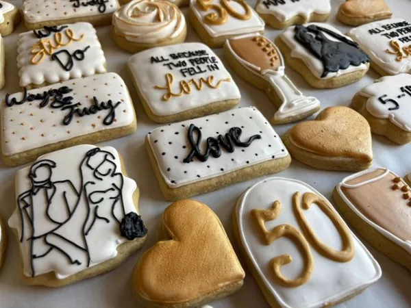 Decorated sugar cookies with wedding-themed designs including a couple, rings, hearts, and '50' anniversary text.