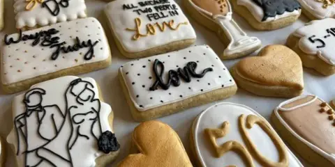 Decorated sugar cookies with wedding-themed designs including a couple, rings, hearts, and '50' anniversary text.