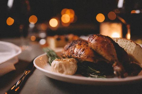 A close-up of a plated roasted chicken dish with garlic and herbs on a white plate.