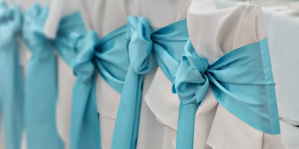 A row of white chair covers tied with light blue satin sashes.