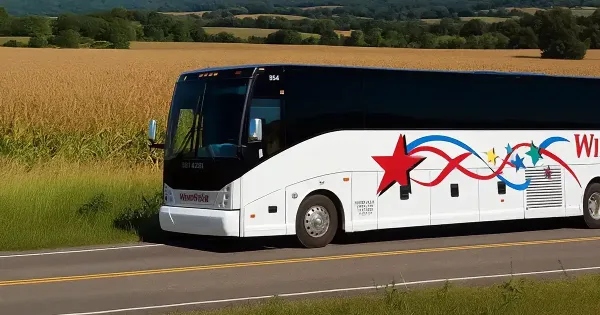 A white Windstar Lines motorcoach driving on a rural road with a cornfield in the background.