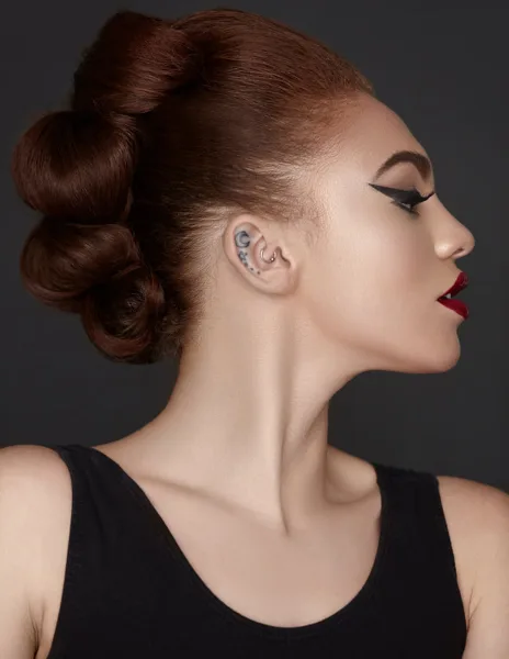 Profile portrait of a model with a styled updo and professional makeup