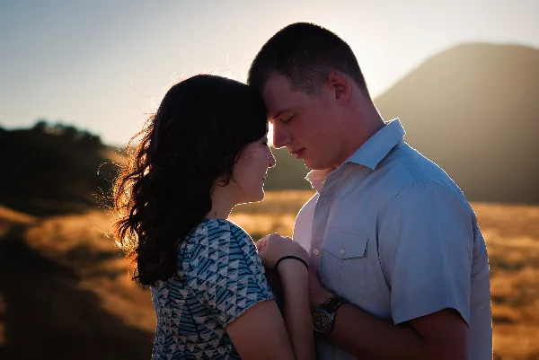 A couple posing for an outdoor engagement photo session at sunset.