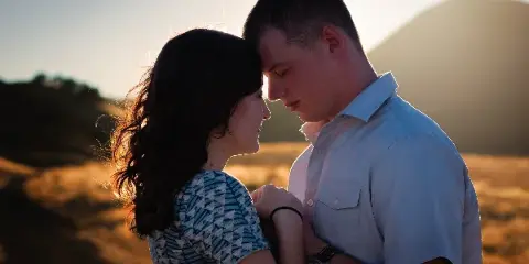 A couple posing for an outdoor engagement photo session at sunset.