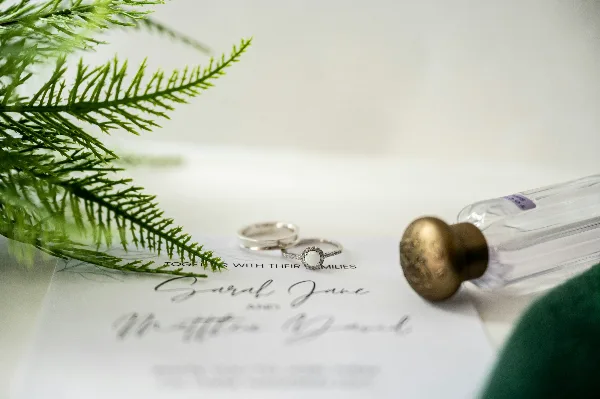 A close-up of a signed wedding certificate with two rings and a quill pen resting on the paper.