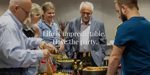A group of people gathered around a table with food and drinks, illustrating a social or corporate event.