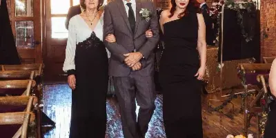 A wedding party walking down the aisle in a rustic event venue with exposed brick walls and wooden floors.