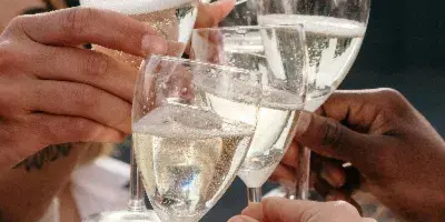 A group of hands holding champagne flutes in a celebratory toast.