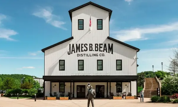 Exterior view of the white James B. Beam Distilling Co. building with a statue in the foreground.