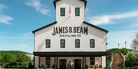 Exterior view of the white James B. Beam Distilling Co. building with a statue in the foreground.