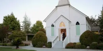 Bride and groom standing at the entrance of a white wedding chapel on their wedding day.