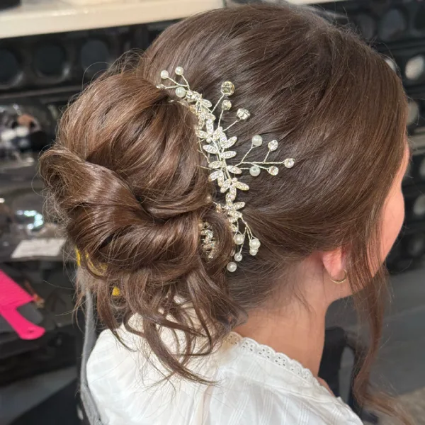 A close-up of a professionally styled bridal updo with a jeweled hair accessory.
