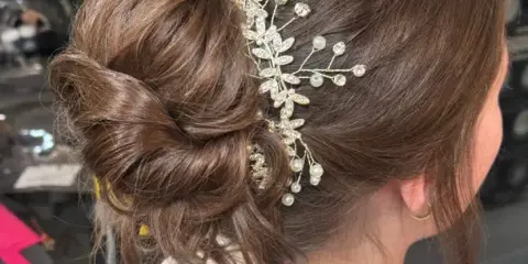 A close-up of a professionally styled bridal updo with a jeweled hair accessory.