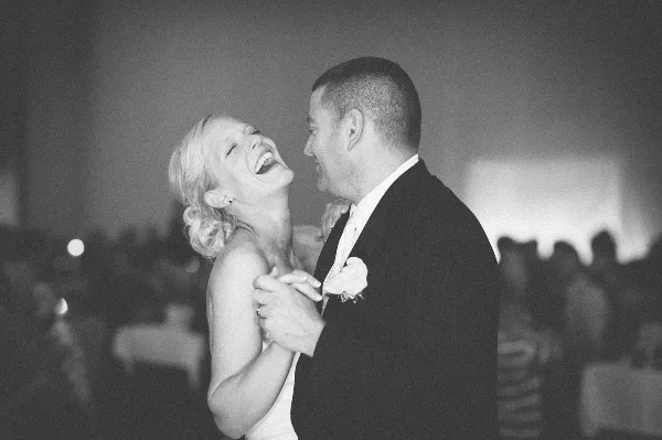 A bride and groom laughing and dancing together at a wedding reception.