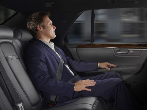 A man in a business suit sitting in the back seat of a luxury car.