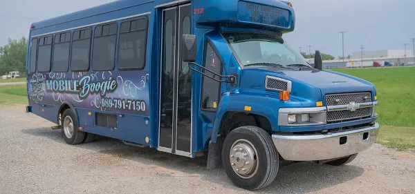 A blue Mobile Boogie shuttle bus parked on a gravel lot.