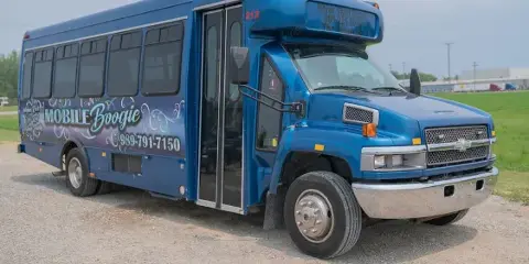 A blue Mobile Boogie shuttle bus parked on a gravel lot.
