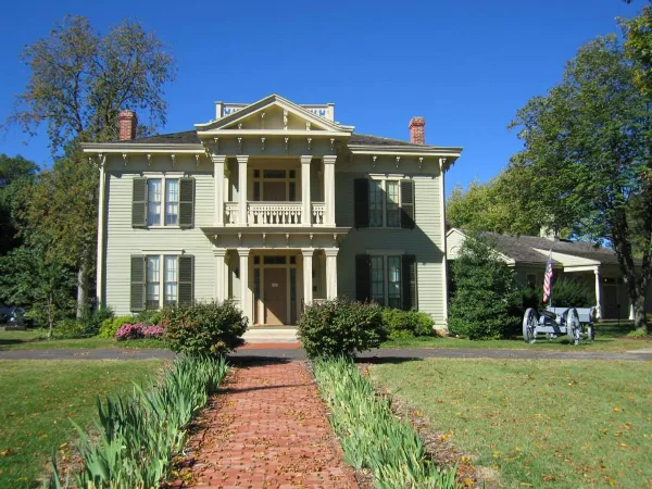 Exterior view of the Graceland Mansion, a historic two-story building with a brick pathway and manicured lawn.