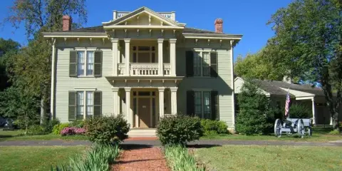 Exterior view of the Graceland Mansion, a historic two-story building with a brick pathway and manicured lawn.