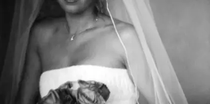 Black and white portrait of a bride in a white dress and veil holding a bouquet of roses.