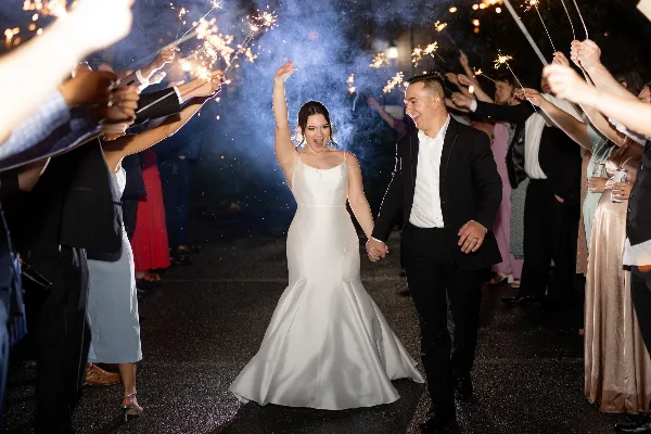 A bride and groom walking through a sparkler tunnel at a wedding reception.