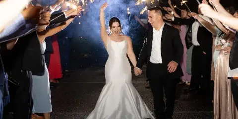 A bride and groom walking through a sparkler tunnel at a wedding reception.