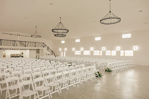 Interior view of a white wedding venue with rows of chairs and chandeliers