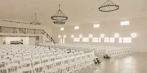 Interior view of a white wedding venue with rows of chairs and chandeliers
