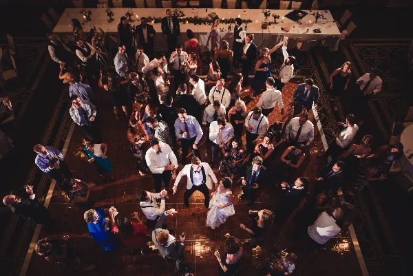 Overhead view of a crowded wedding dance floor with guests dancing under warm lighting.