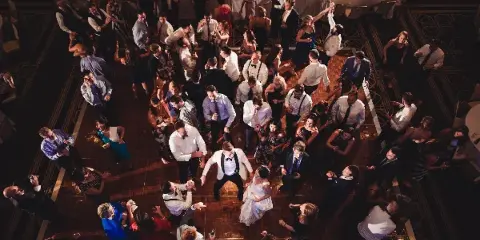 Overhead view of a crowded wedding dance floor with guests dancing under warm lighting.
