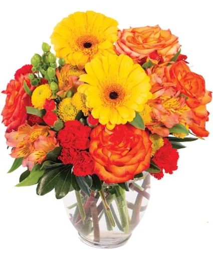 A vibrant floral arrangement in a clear glass vase featuring yellow gerbera daisies, orange roses, and red carnations.