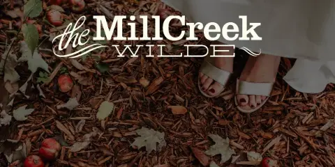 Bride's feet in a white dress and sandals standing on wood mulch with fallen apples