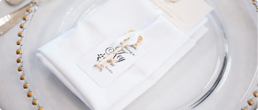 Elegant table setting with white napkin and gold-beaded charger for a catered event