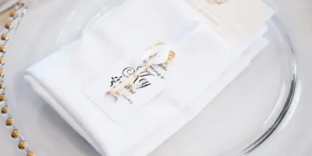 Elegant table setting with white napkin and gold-beaded charger for a catered event