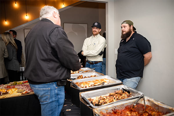 Catering staff serving guests at a buffet event with trays of food.